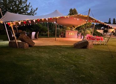 Spacious event tent with white drapes and floral decorations