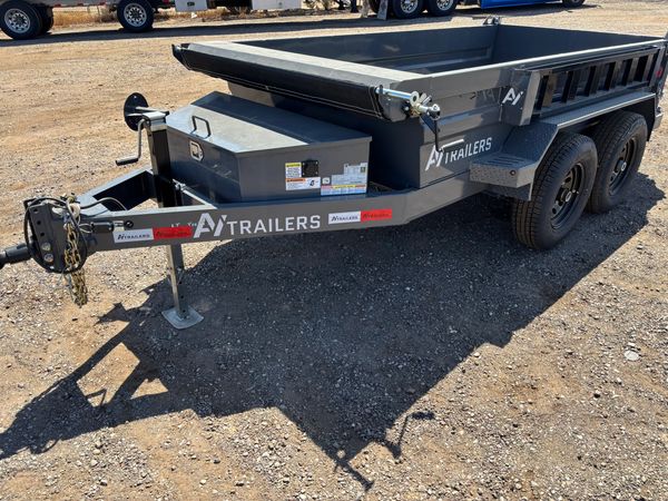 Gray AI Trailers dump trailer parked on dirt ground.