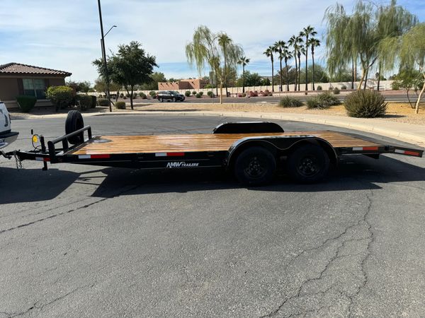 Flatbed car trailer parked on a suburban street under clear skies.