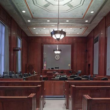 Empty courtroom with wooden paneling and furniture.