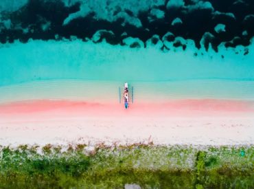 Aerial view of a boat on a vibrant beach with turquoise waters.