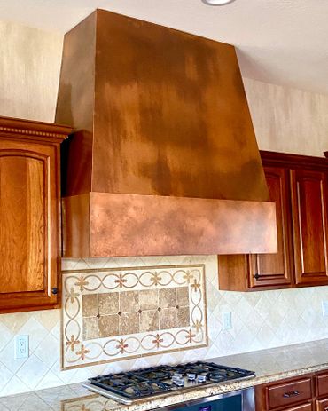 Custom copper kitchen range hood by Tin Works with warm patina finish and clean design