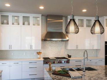 Custom stainless steel range hood and duct cover by Tin Works in modern white kitchen