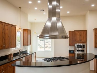 Custom stainless steel island range hood by Tin Works in luxury residential kitchen