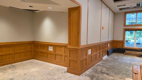 Empty room with wood paneling and concrete floor under construction.