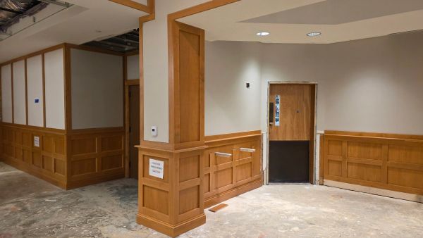 Indoor construction area with wooden paneling and a door under renovation.