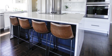 Solid surface countertop in modern white kitchen with hardwood flooring.