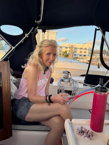 A woman sitting on a boat with a relaxed smile during sunset.