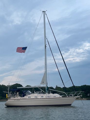 Sailboat named SOY AMADA with an American flag on a calm water body.