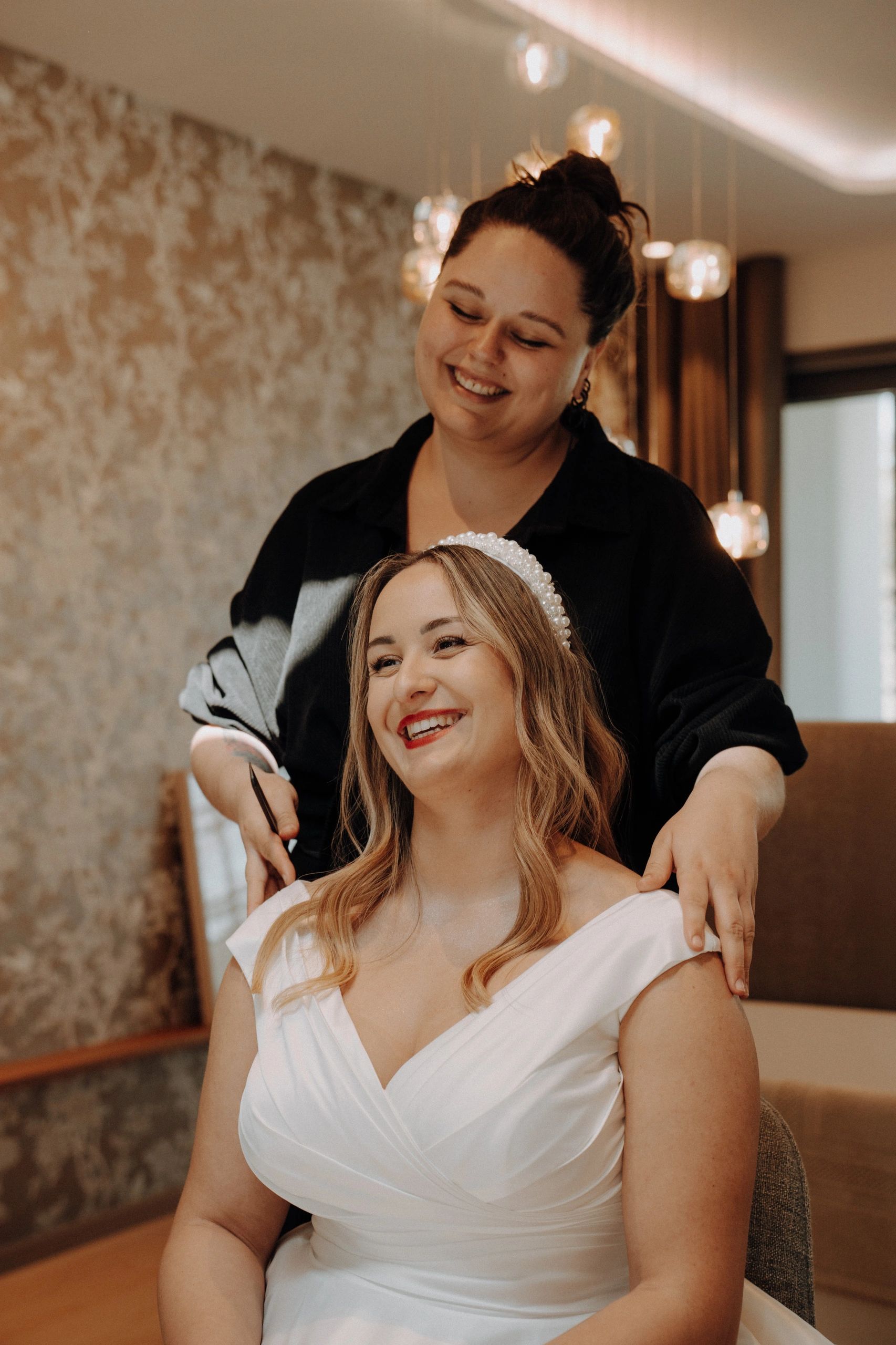 Smiling bride getting her hair done with a pearl headband.
