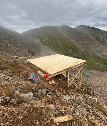 Remote timber helipad construction on rugged mountain terrain by Blue Collar Vertical Industries.