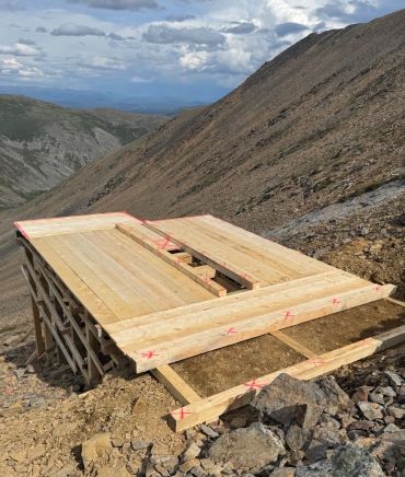 Custom timber helipad platform construction in remote mountain terrain by Blue Collar Vertical Industries.