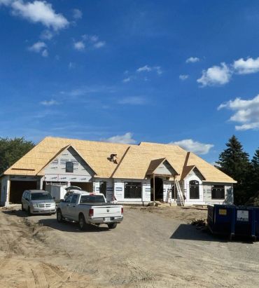 Residential home under construction with roof framing and exterior construction work by Blue Collar Vertical Industries.