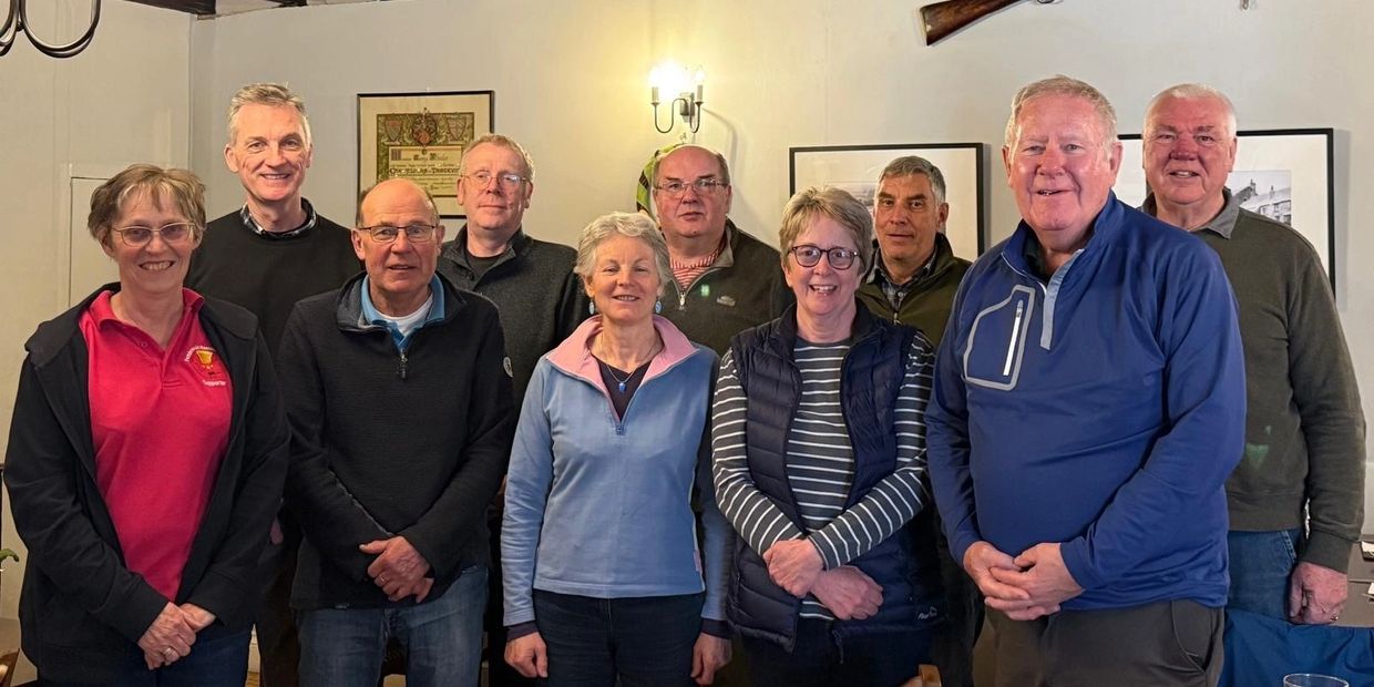 A group of ten adults posing for an indoor photo, smiling warmly.