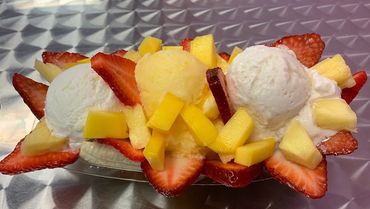 Colorful fruit dessert with ice cream scoops and fresh fruit.