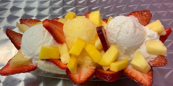Colorful fruit dessert with ice cream scoops and fresh fruit.