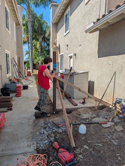 A man working on construction in an alley between buildings.