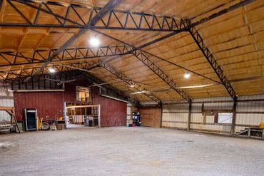 Spacious barn interior with gravel floor and metal roof beams.