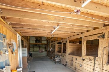 Interior of a clean, well-lit wooden horse stable with multiple stalls.