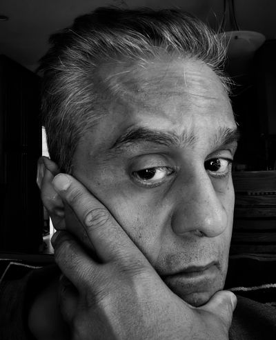 Black and white close-up portrait of a contemplative man resting his face on his hand.