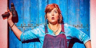 Surprised woman holding a power drill against a blue door.