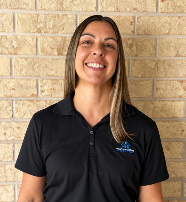 Smiling woman in black polo shirt with logo.