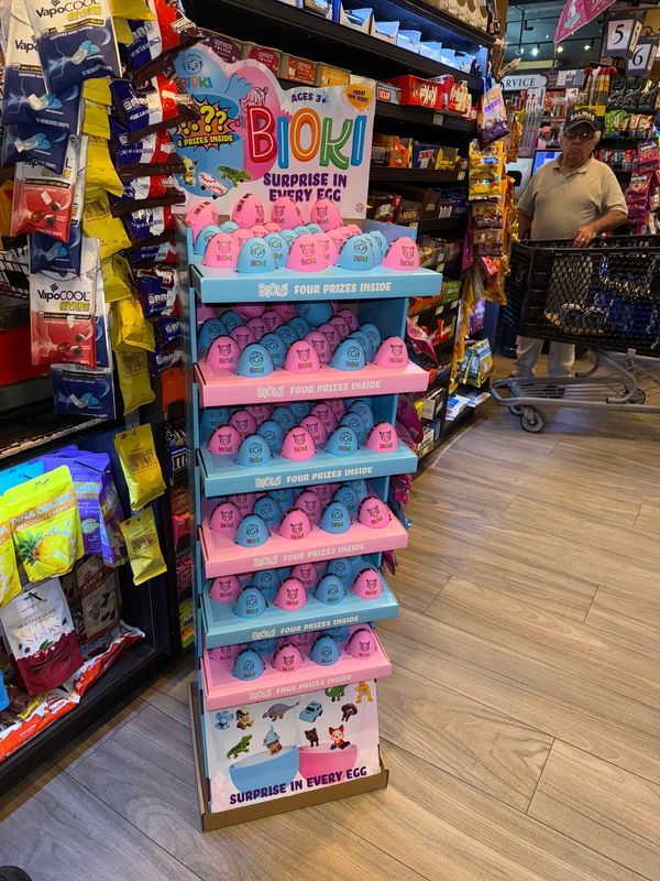 Colorful Bioki surprise eggs displayed on a store shelf with a shopper in the background.