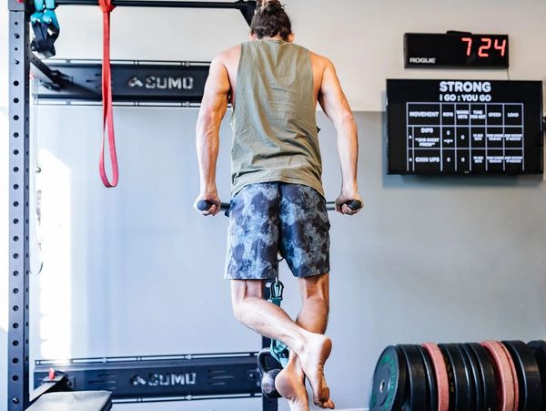 Man doing dip exercise in a gym barefoot.
