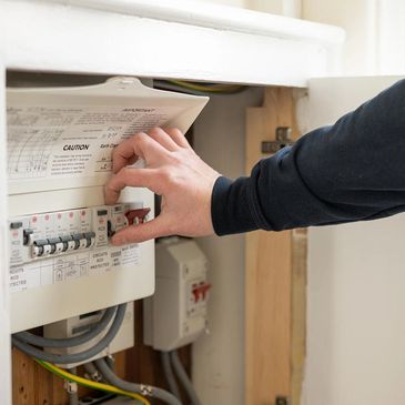 Person adjusting a circuit breaker in an electrical panel.