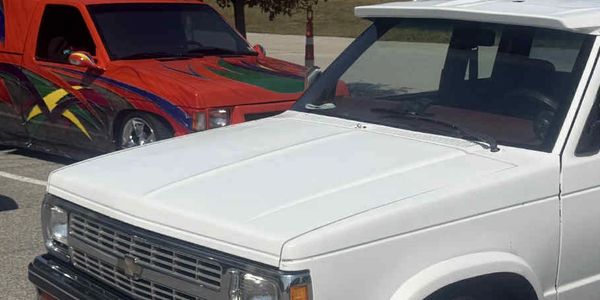 Three customized vehicles parked outdoors in daylight.