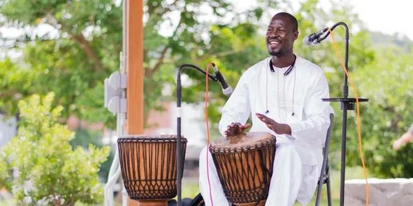 A Man Sitting in Front of a Microphone Holding a Drum