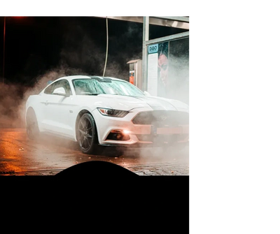 White sports car surrounded by mist at night in a car wash.