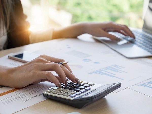 Close up businesswoman using computer and laptop to do math finance on wooden desk in office 