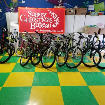 Bicycles lined up in front of Surrey Christmas Bureau boxes.