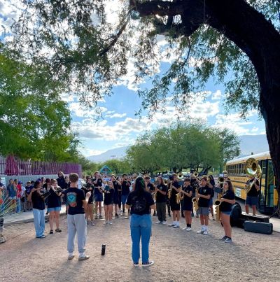 High school band practicing outdoors near a school bus.