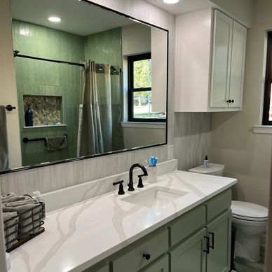 Modern bathroom with green tiles and a white countertop.