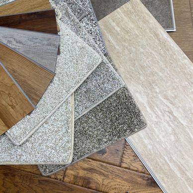 Various carpet and flooring samples arranged on wooden floor.