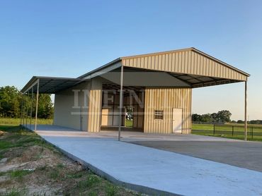 A large metal carport with a concrete driveway in a rural area.