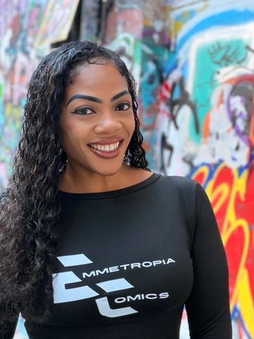 Smiling woman with curly hair in front of colorful graffiti.