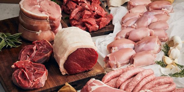 Various raw meats including beef, pork, chicken, and sausages on wooden boards.