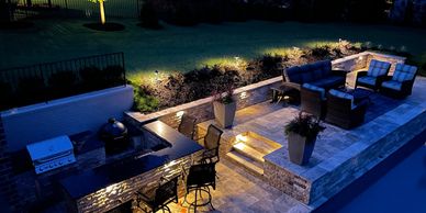 Well-lit outdoor patio with seating and grill at night.