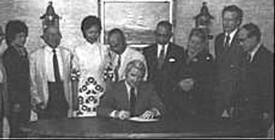 Group photo with a man signing a document at a table.
