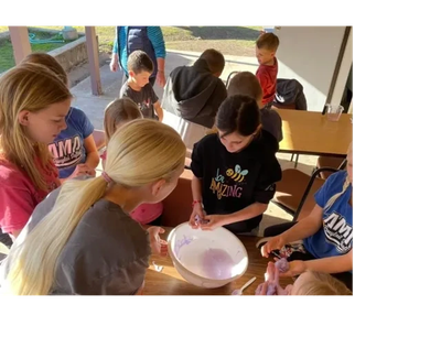 Children gathered around a bowl engaged in a project.