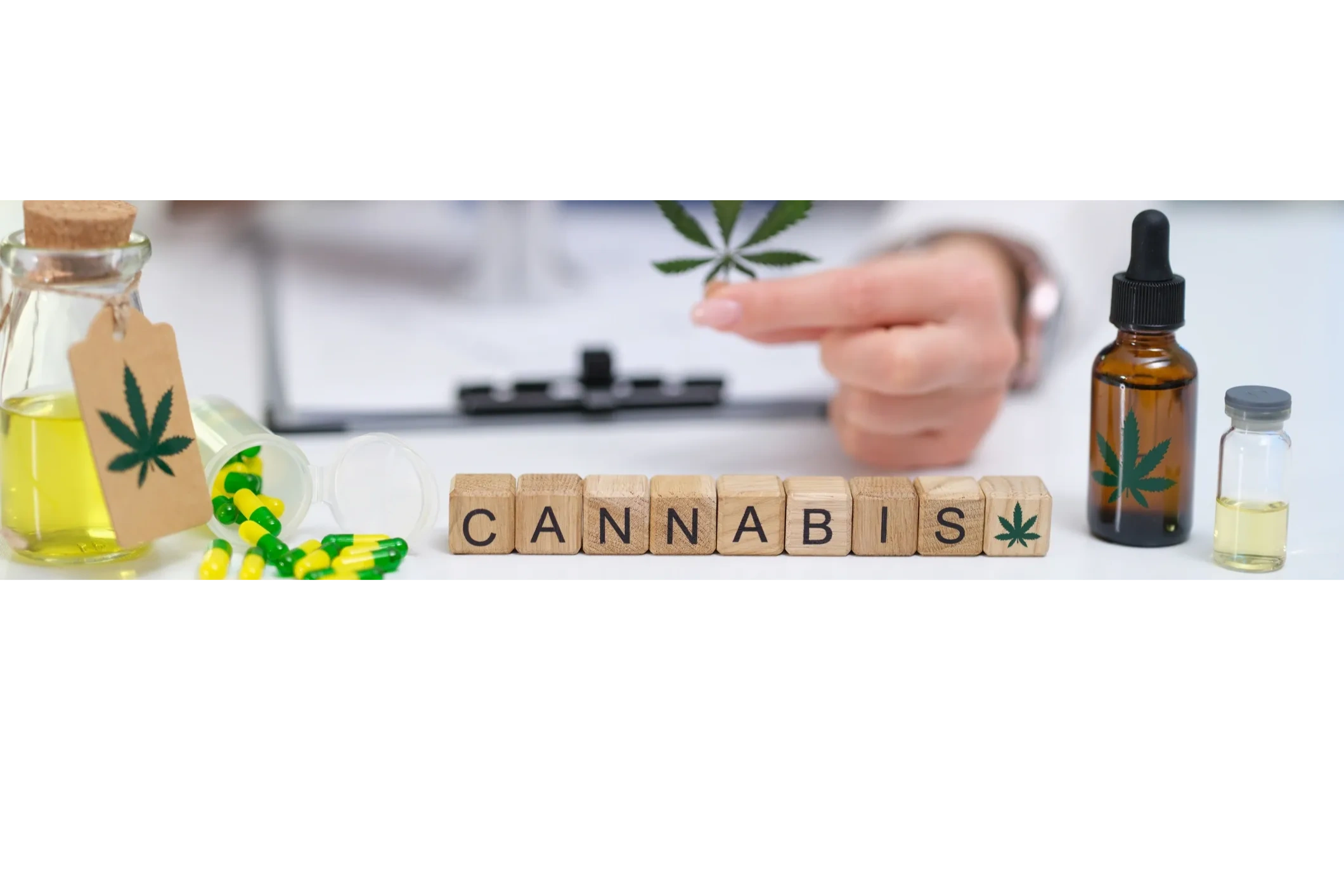 Les lettres du mot cannabis sur des blocs de bois, huile et gélules de cannabis médical
