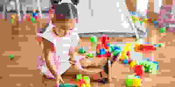 Young beautiful toddler sitting on the floor playing with building blocks at kindergarten