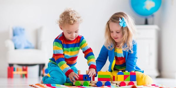 Children playing with wooden train. Toddler kid and baby play with blocks, trains and cars.