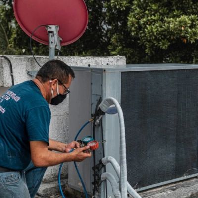 Technician inspecting an HVAC unit outdoors.