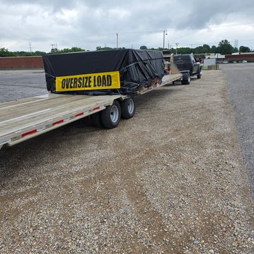 A truck towing a large covered load with an "OVERSIZE LOAD" sign.