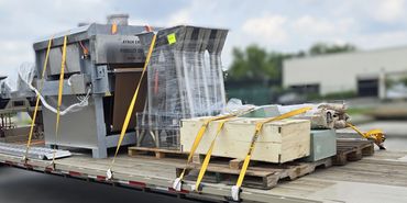 Large industrial equipment securely strapped on a flatbed trailer for transport.