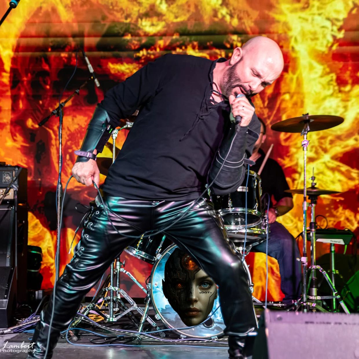 Energetic rock singer passionately performing with fiery backdrop and futuristic drum design.